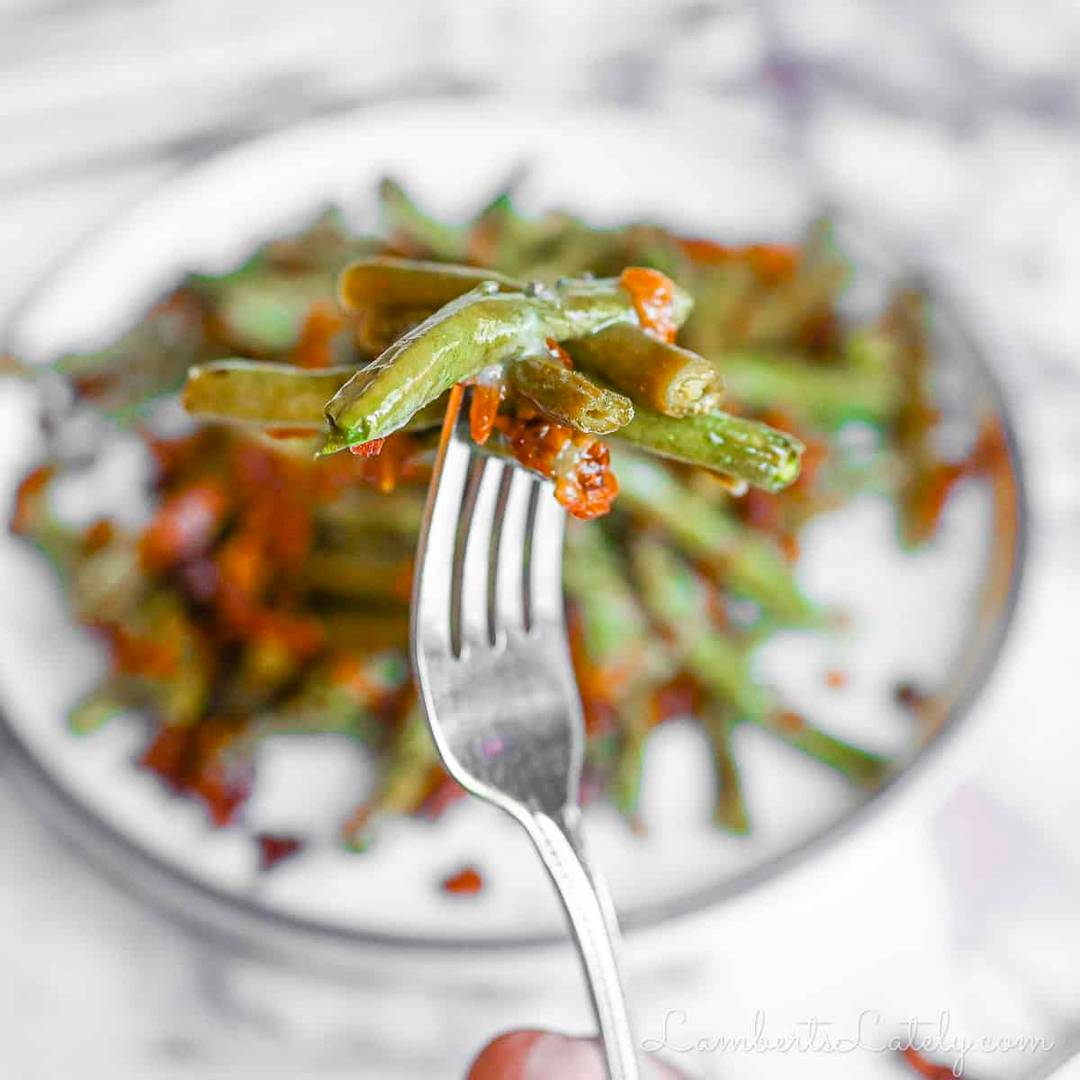 holding a fork of green beans and bacon.