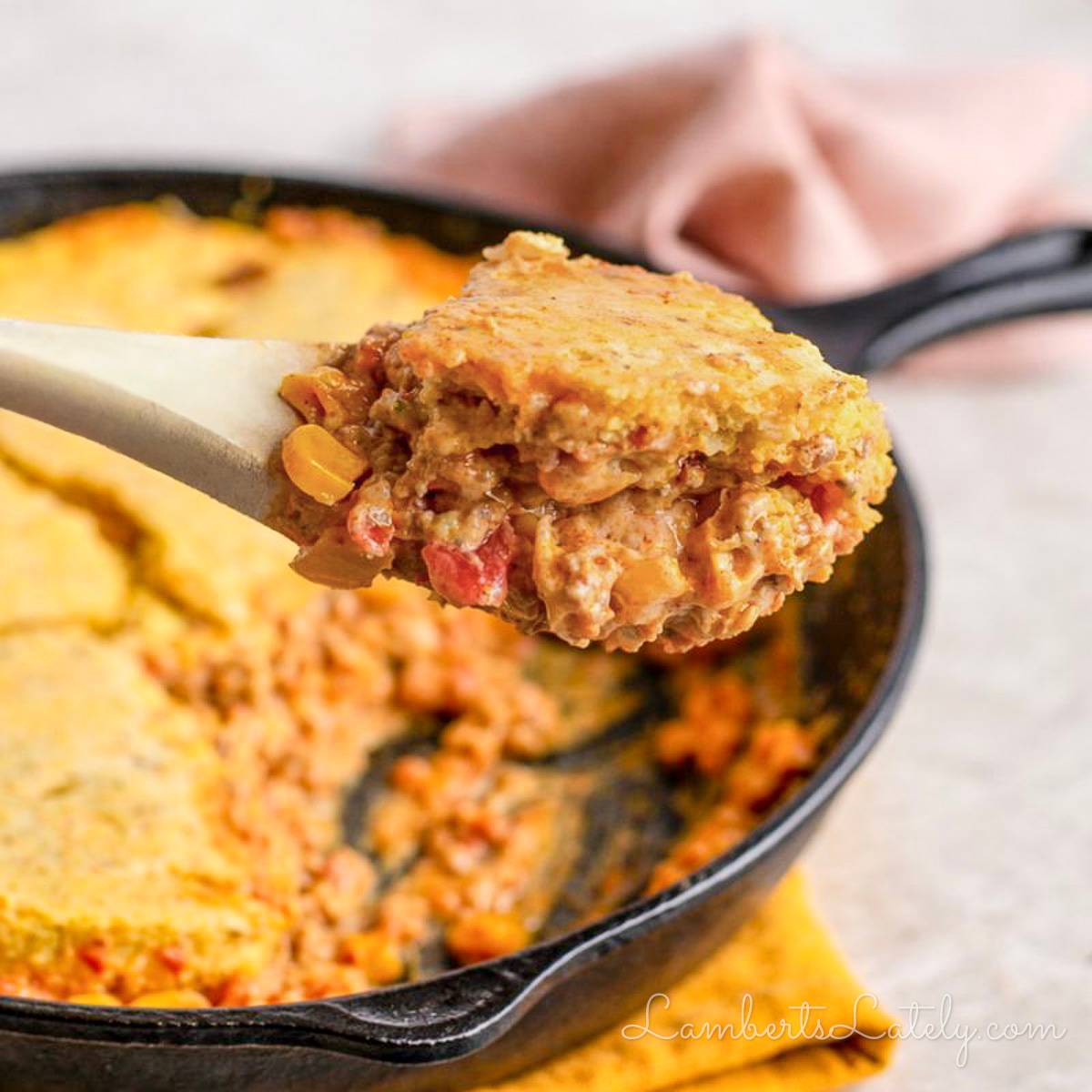 holding a spoonful of cowboy casserole topped with cornbread.