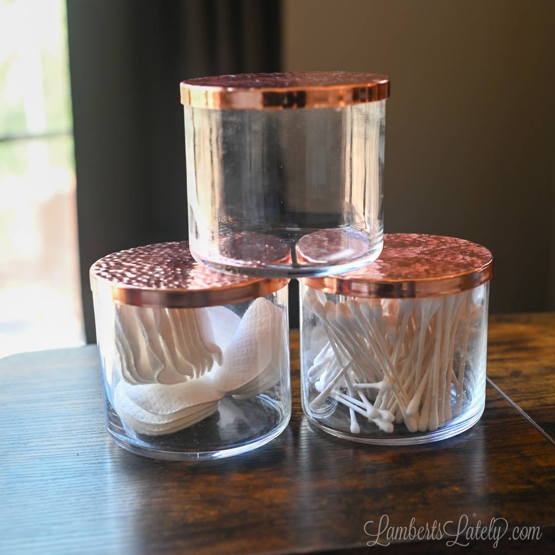 3 empty candle jars filled with bathroom products.