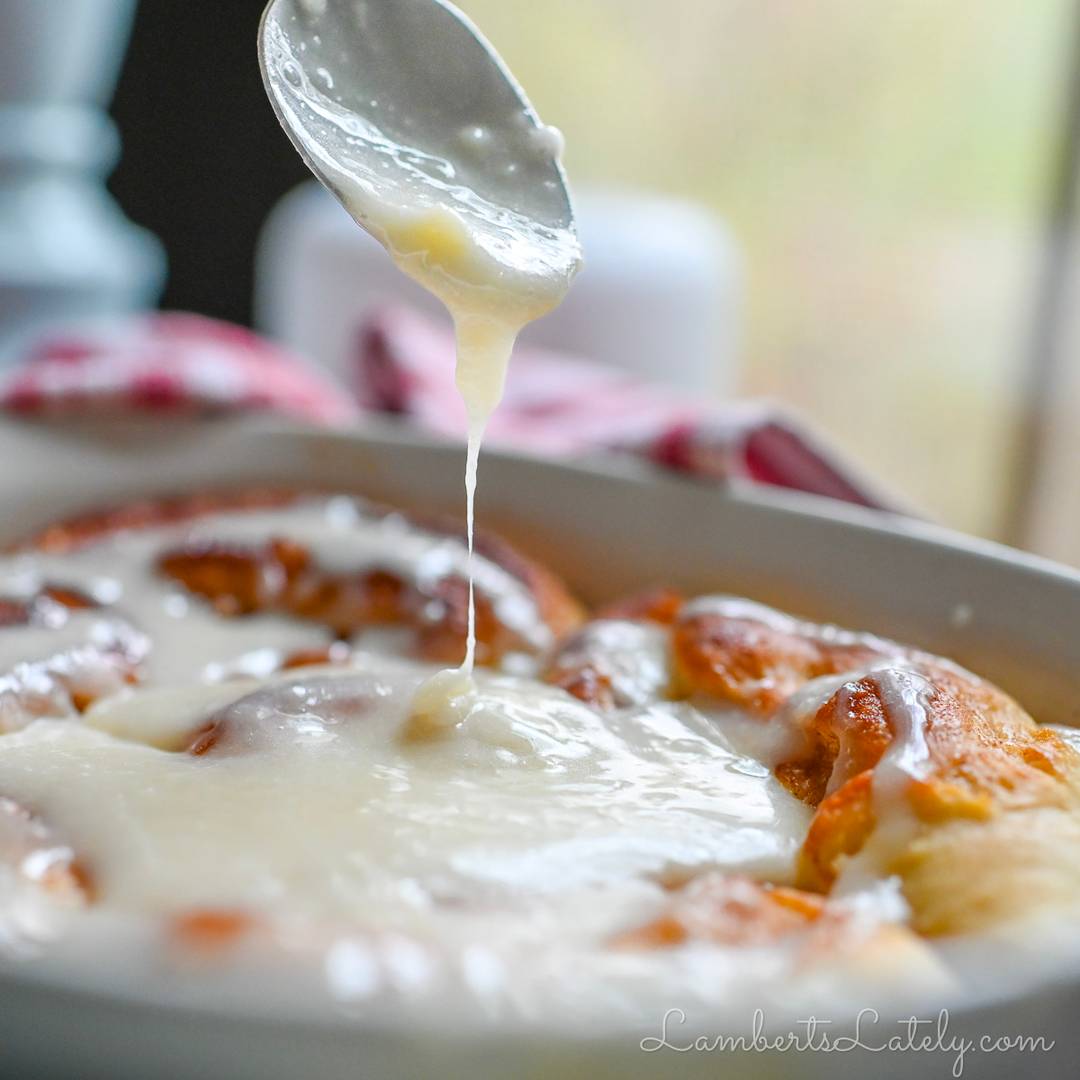 drizzling cream cheese frosting on cinnamon rolls.