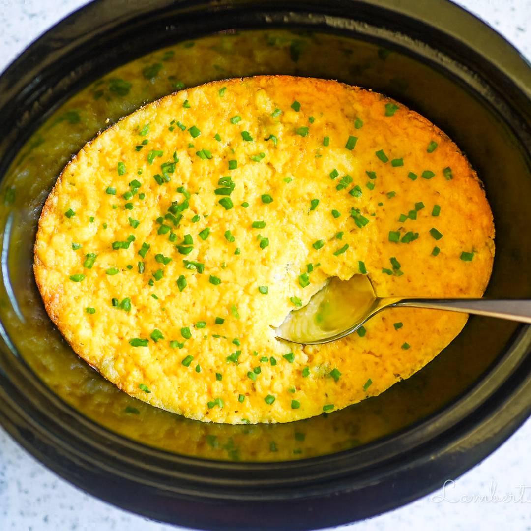 corn casserole in a crock pot, covered in green onions.