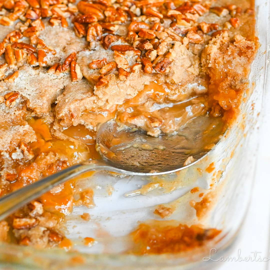 caramel apple dump cake with a spoon in a baking dish.