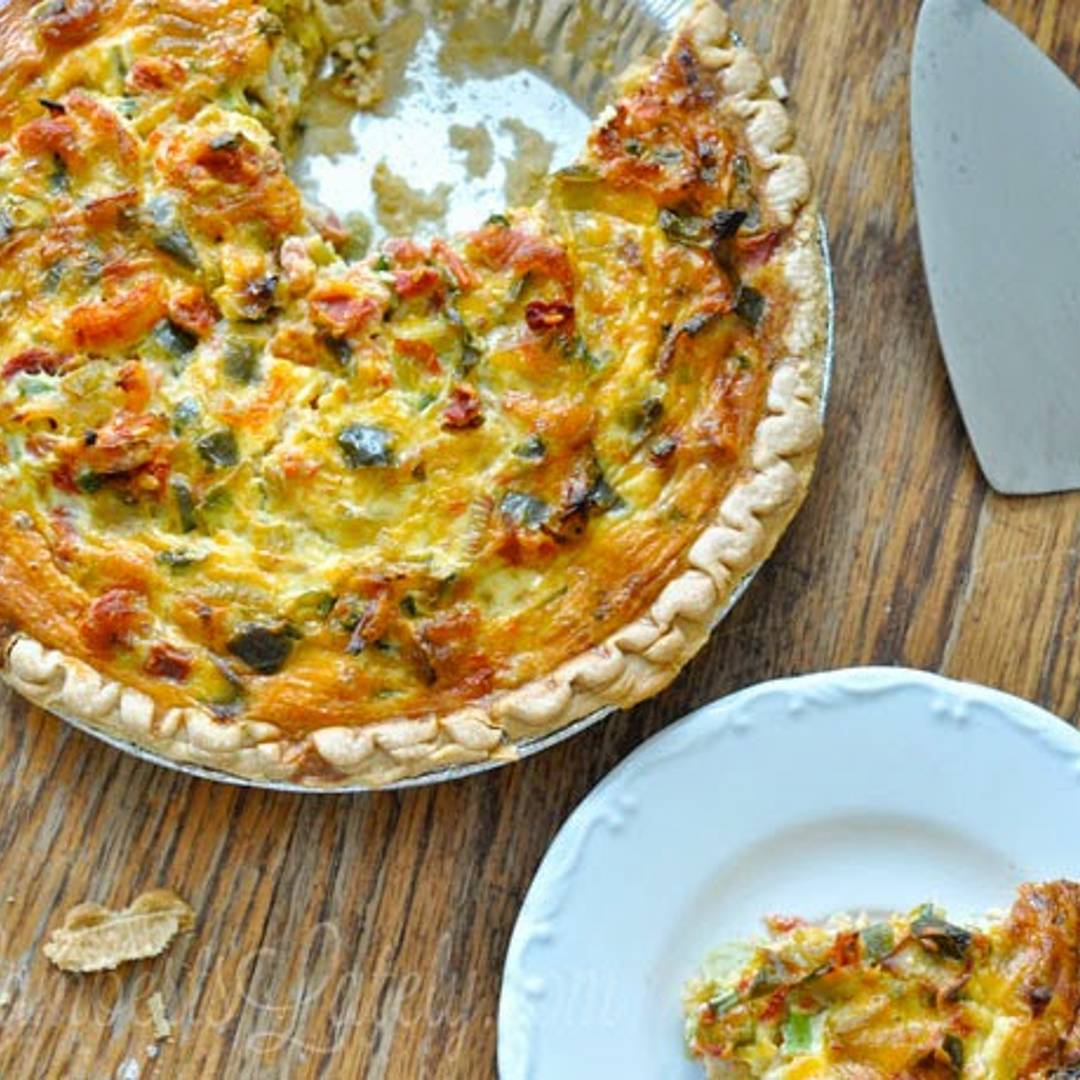 crawfish quiche with a piece missing, piece on a serving dish, serving utensil.
