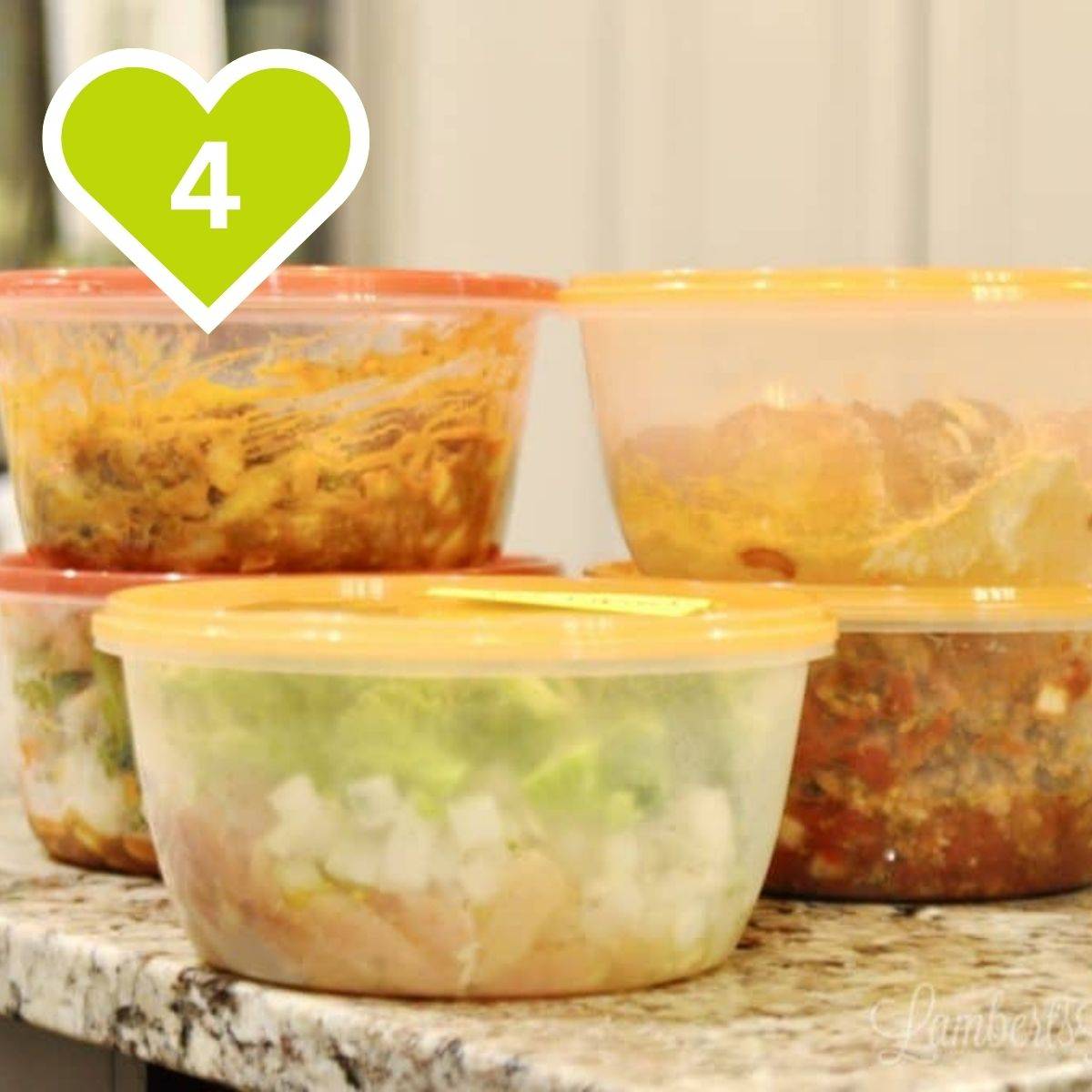 Clear plastic food storage containers filled with prepped meal prep food lined up on a granite countertop.