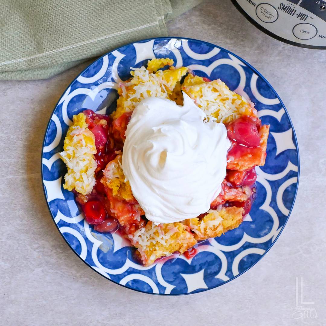tropical dump cake on a plate, topped with whipped cream.