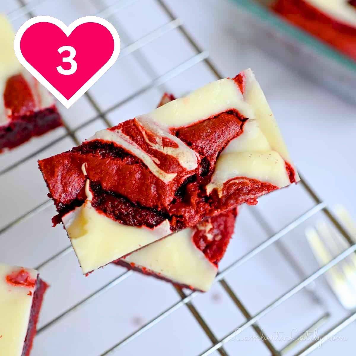3 - red velvet brownie with cream cheese swirl stacked on a baking rack.