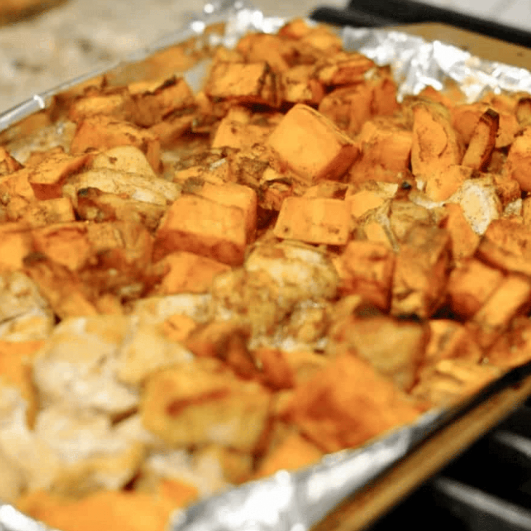 barbecue chicken and sweet potatoes on a sheet pan lined with foil.