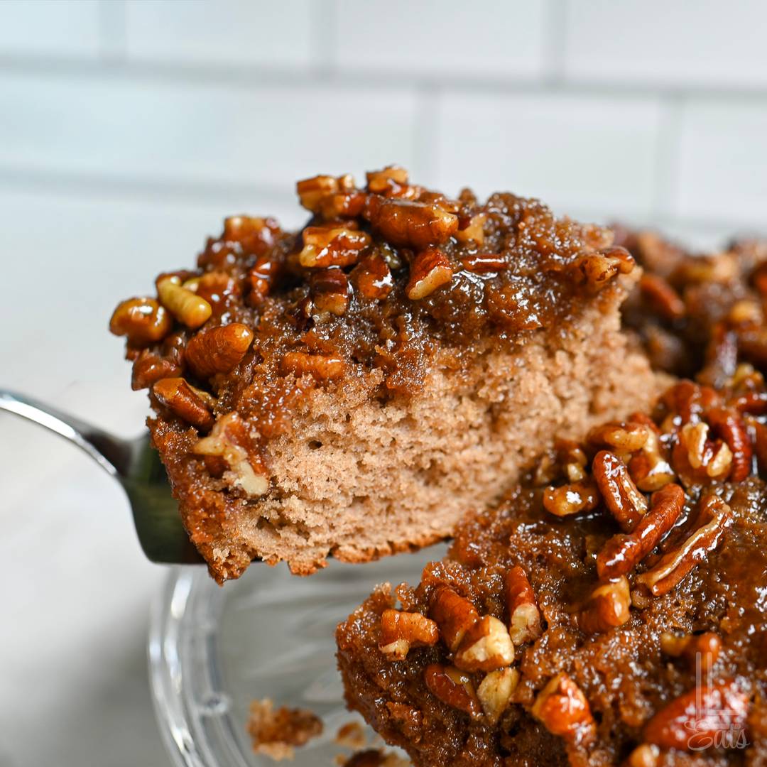 Slice of pecan upside-down cake topped with a gooey brown sugar pecan glaze.