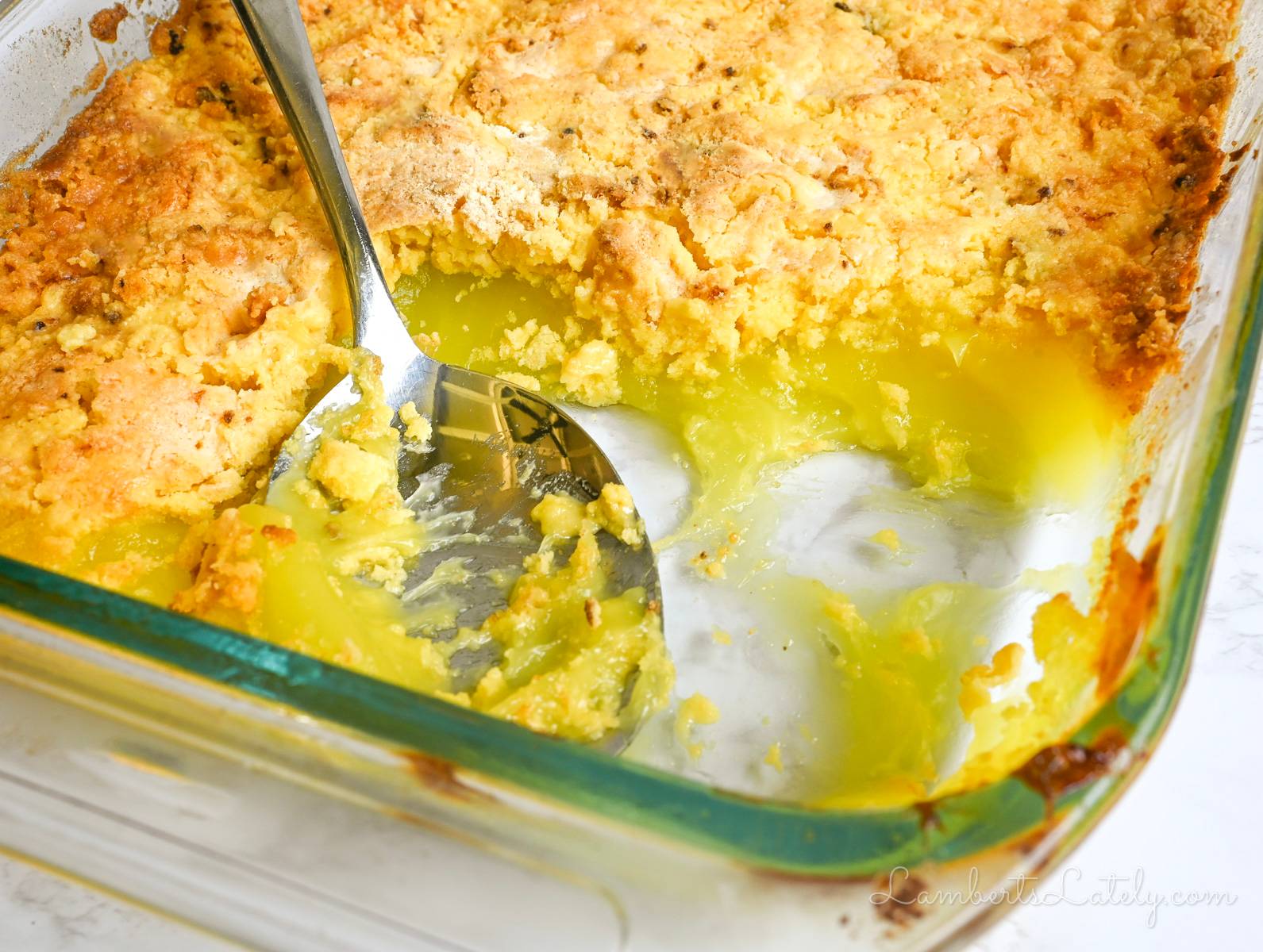 lemon dump cake in a baking dish, with spoon.