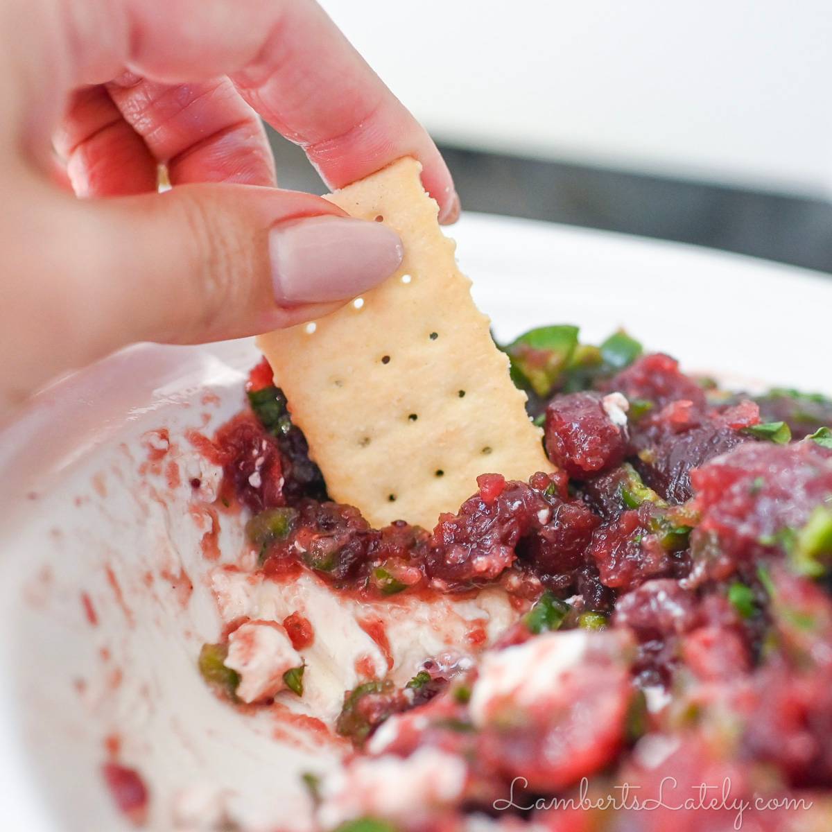 dipping a cracker in cranberry jalapeno dip.