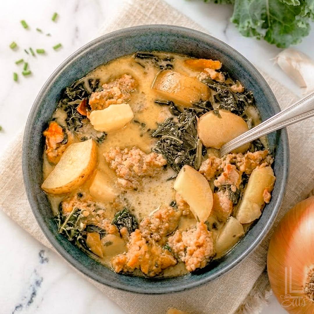 Bowl of creamy Zuppa Toscana with sausage, potatoes, and kale.