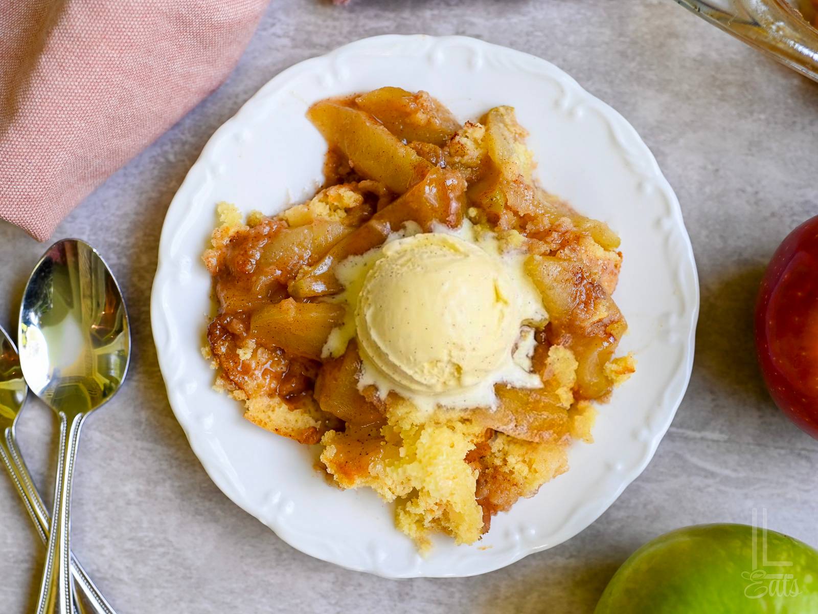apple cobbler on a plate, topped with ice cream.