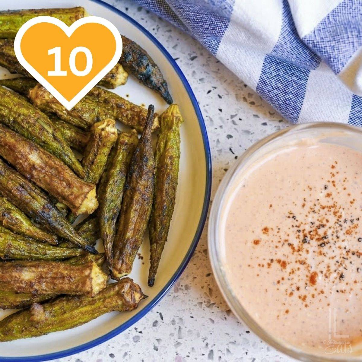 10 - whole okra cooked on a plate, next to a bowl of dipping sauce.