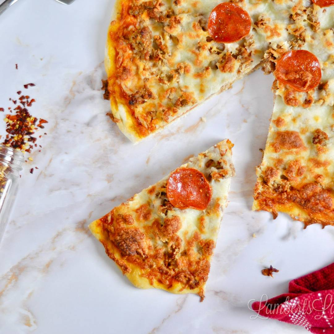 Pepperoni and sausage pizza with several slices removed, served on white parchment paper.