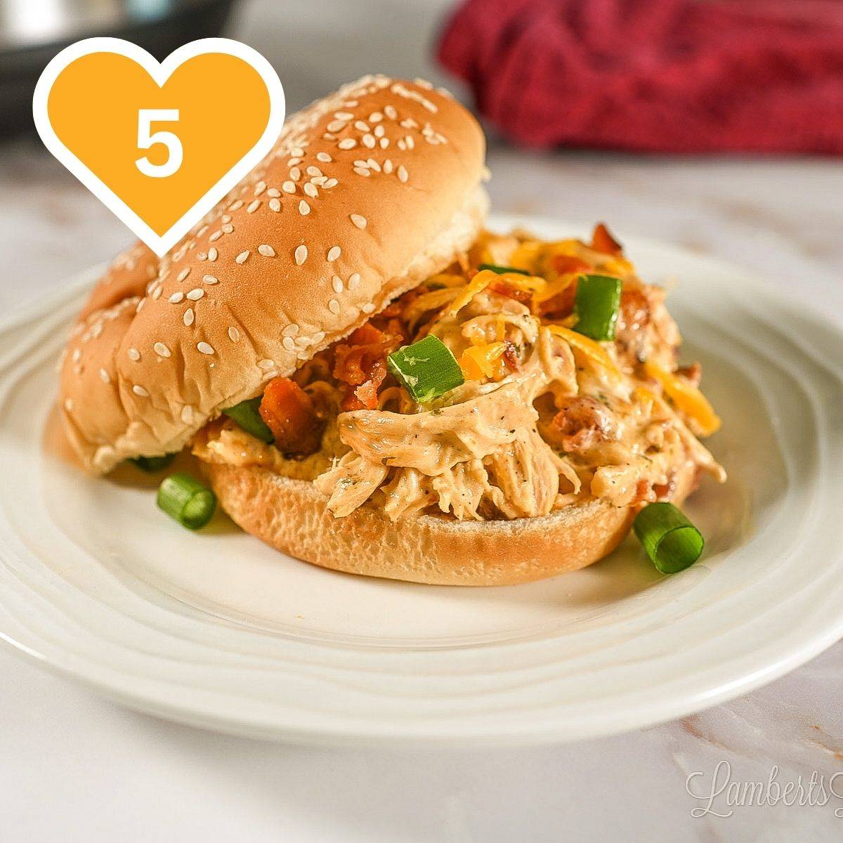 5 -  pulled chicken sandwich topped with cheese on a sesame seed bun.