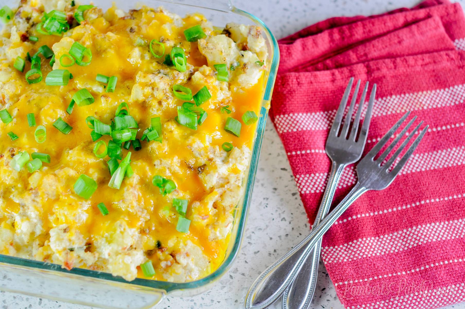 mashed potatoes, covered in cheese and green onions, in a baking dish.