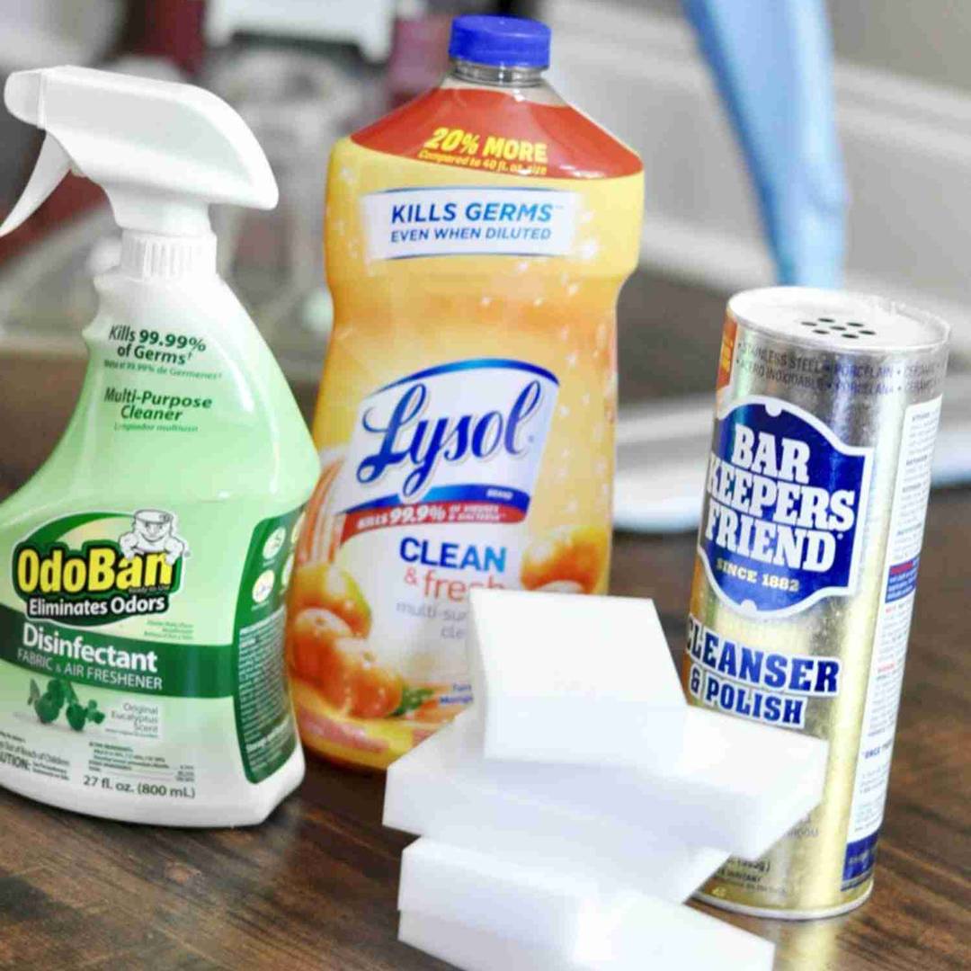 A collection of household cleaning supplies, including OdoBan disinfectant spray, Lysol multi-surface cleaner, Bar Keepers Friend cleanser, and a stack of white melamine foam sponges.