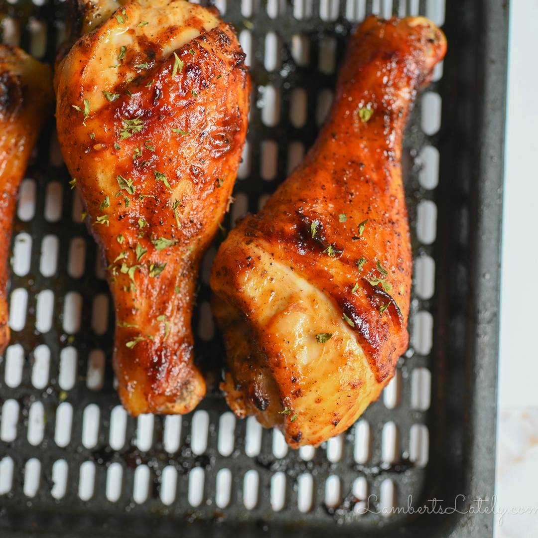 two baked chicken legs on an air fryer pan.