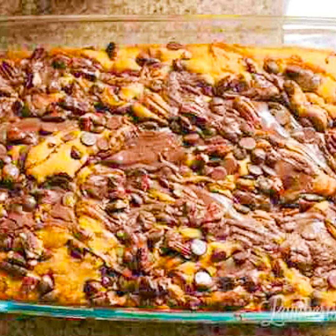 Pumpkin earthquake cake with swirls of chocolate, cream cheese, and pecans in a baking dish.