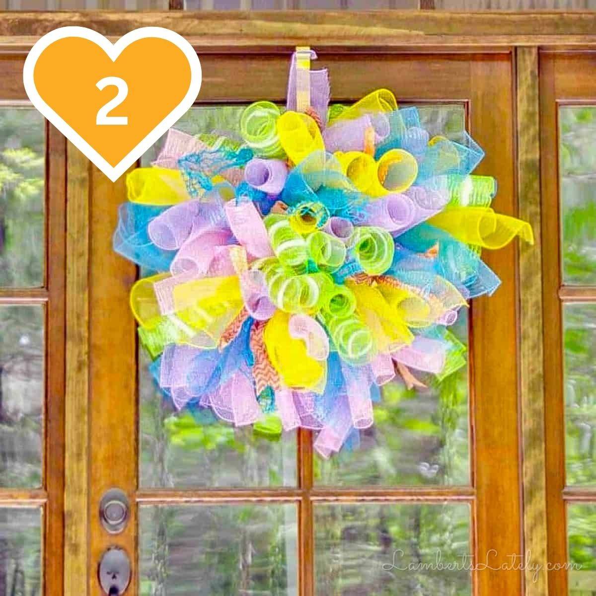 2 - Colorful mesh wreath with pastel ribbon hanging on a front door.