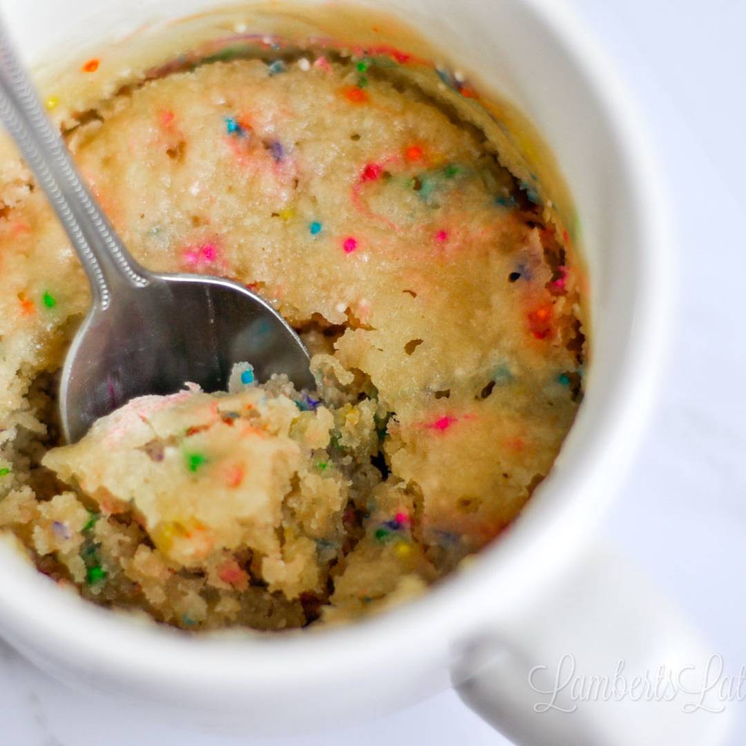 vanilla mug cake with sprinkles in a coffee mug.