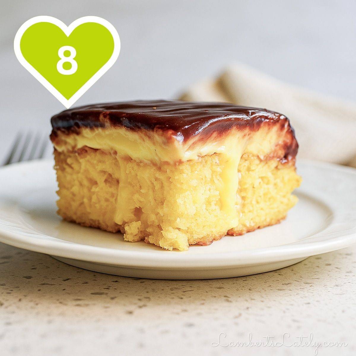 Slice of poke cake on a white plate showing layers of yellow cake, creamy filling, and a chocolate topping.