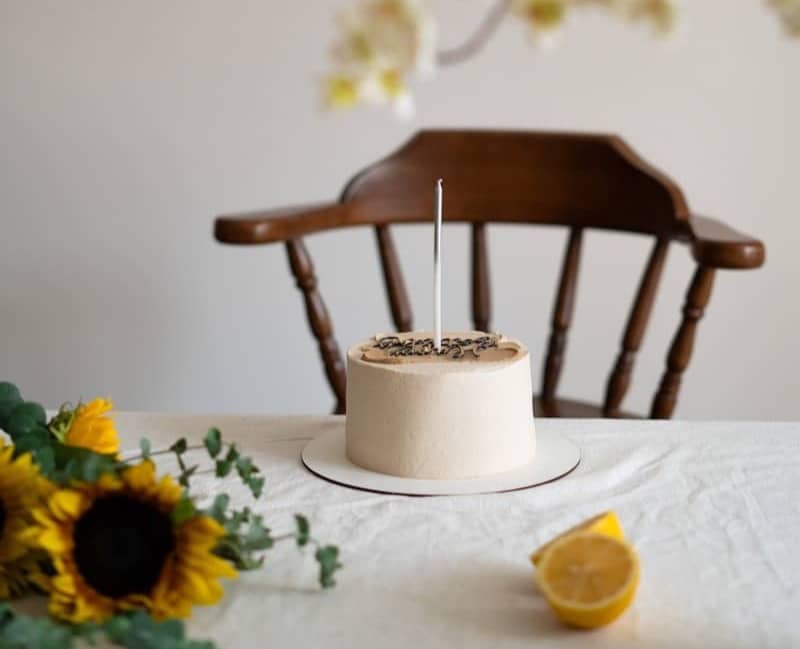 A simple cake with one candle and sunflowers.