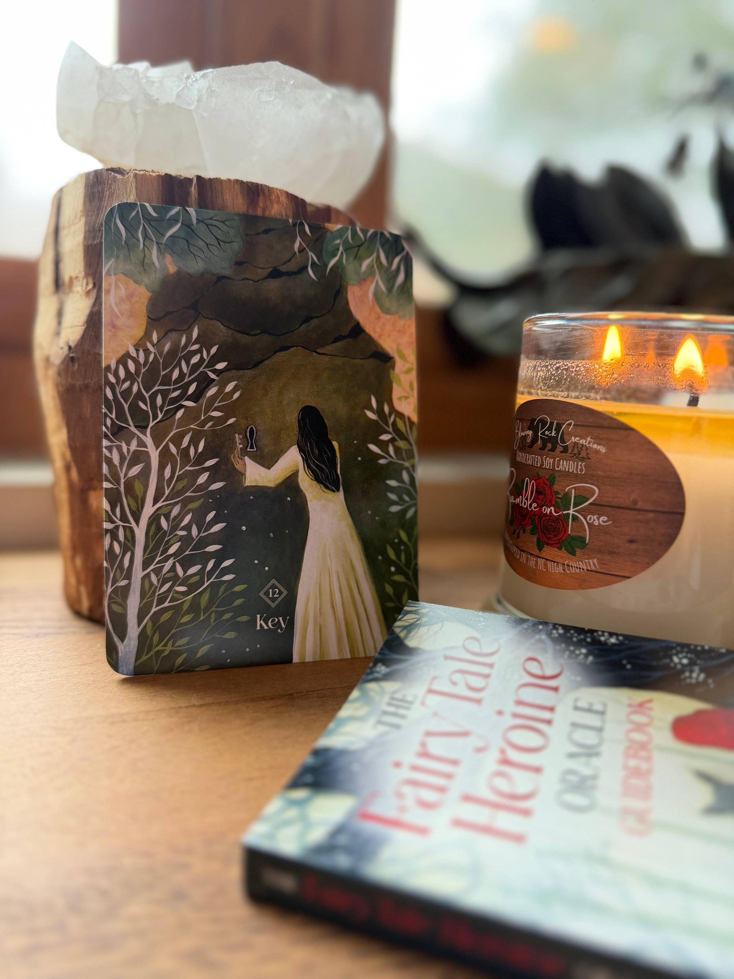 A woman with flowing black hair stands in front of a wall of rock. There is a key in her left hand, and a keyhole in the stone. All around her are branches and leaves.