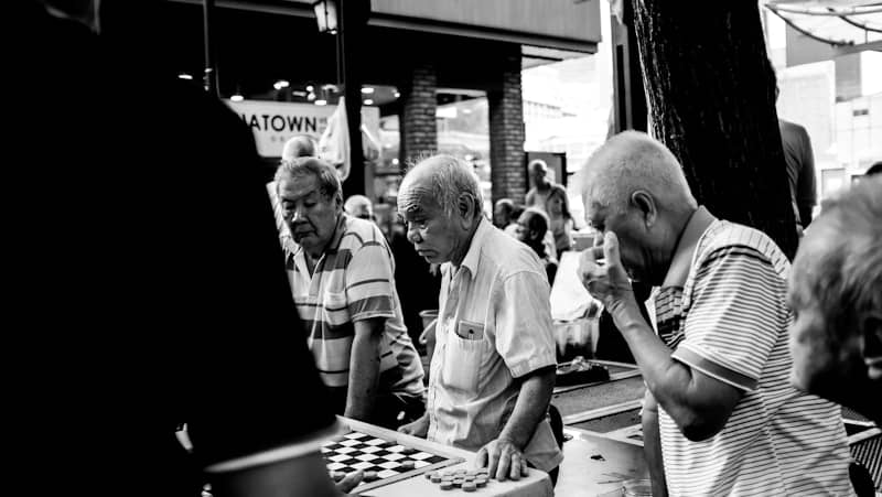 greyscale photo of men playing board game