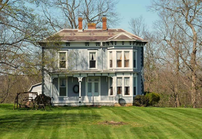 A light blue victorian house with a porch