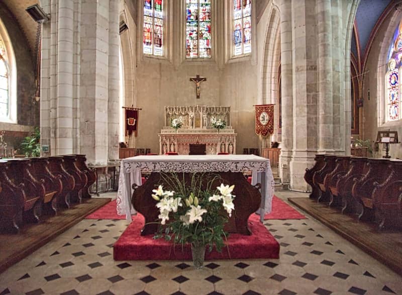 Ornate church interior with an altar and stained glass windows.