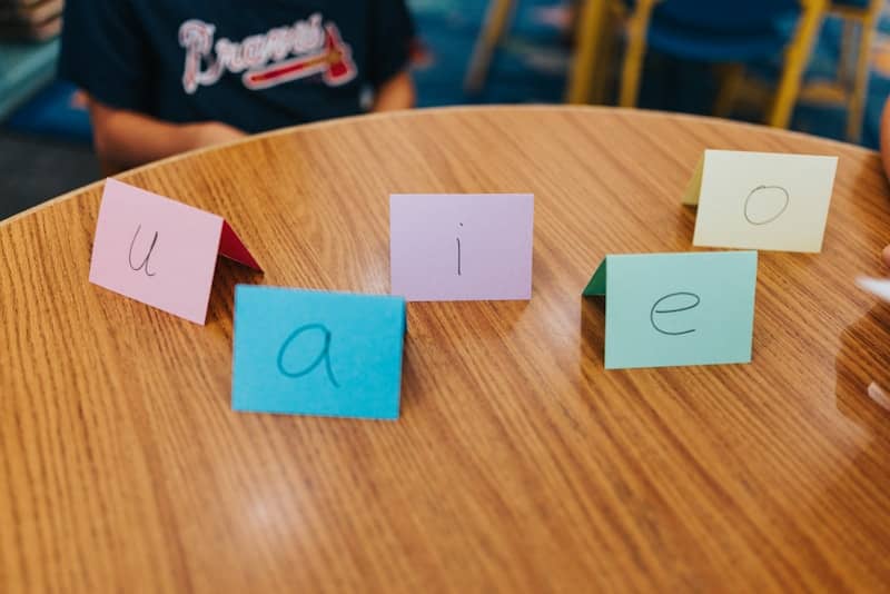Five colorful cards with vowels on a wooden table.