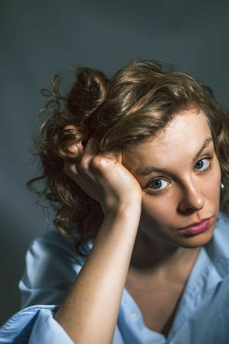 A young woman rests her head on her hand.