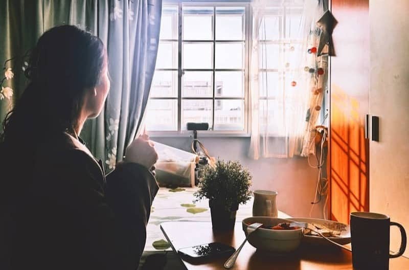 Woman enjoying morning coffee by window light.