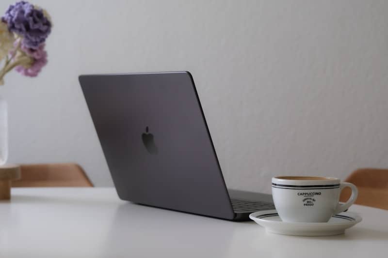 Laptop and coffee cup on a white table.