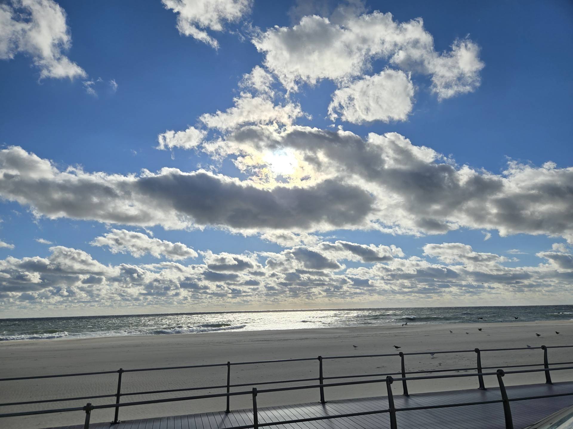 A view of of the beach and ocean with a blue sky and clouds.