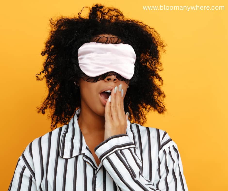 Woman with a sleep mask and striped pajamas yawning against a yellow background