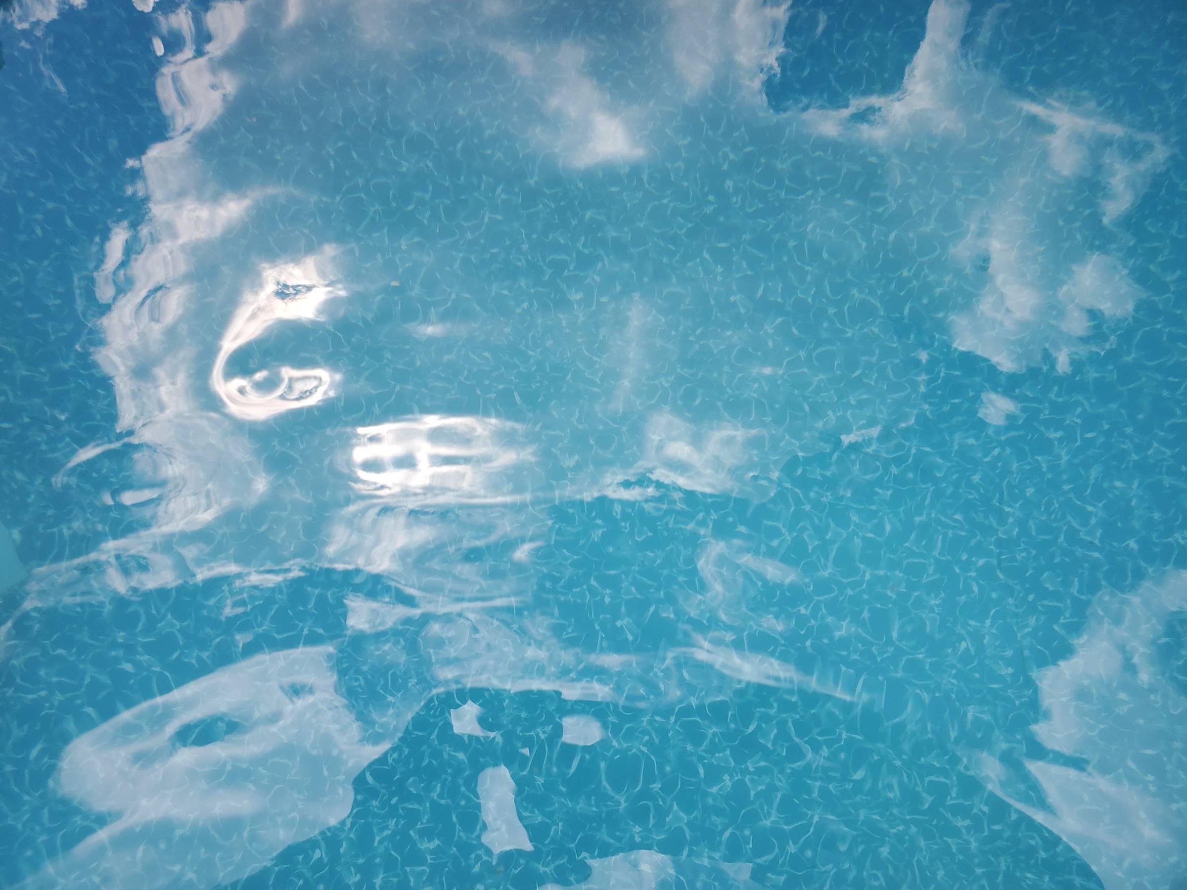 Clouds reflected in blue pool water