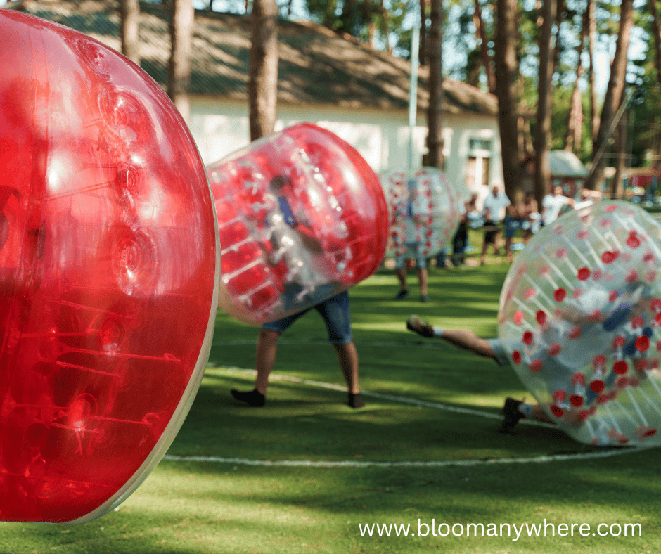 People in large red and clear bubbles playing a game outdoors