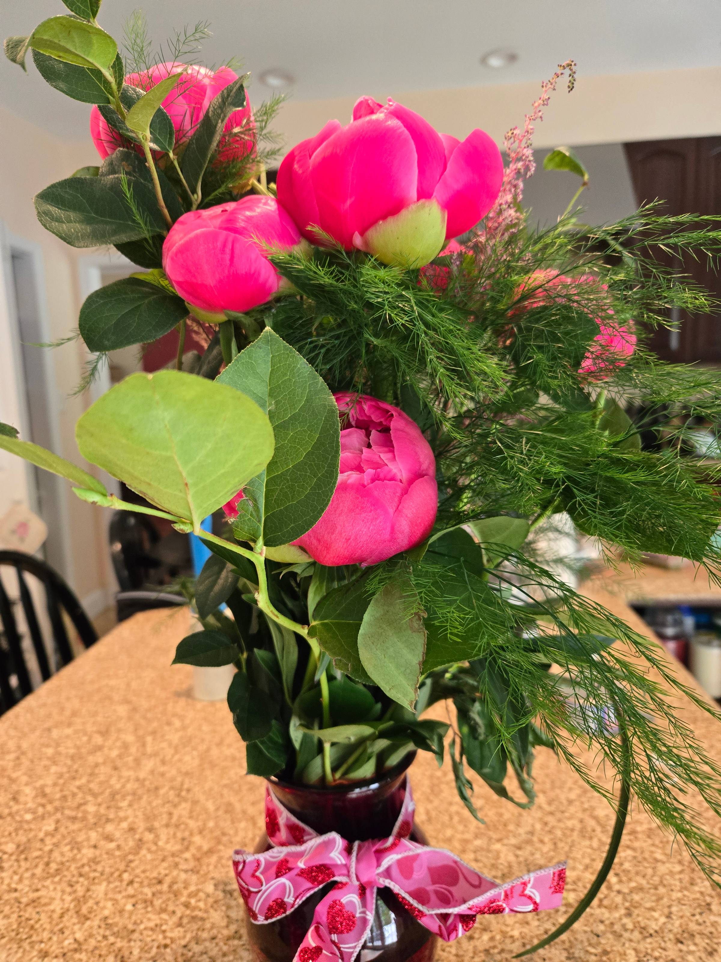 A bouquet of peony buds in a red vase