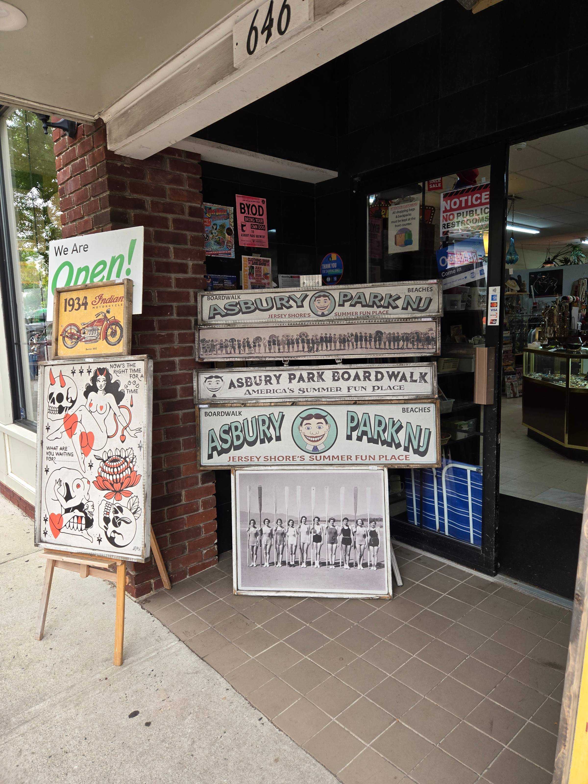 The outside of a storefront with multiple signs depicting Asbury Park, NJ.