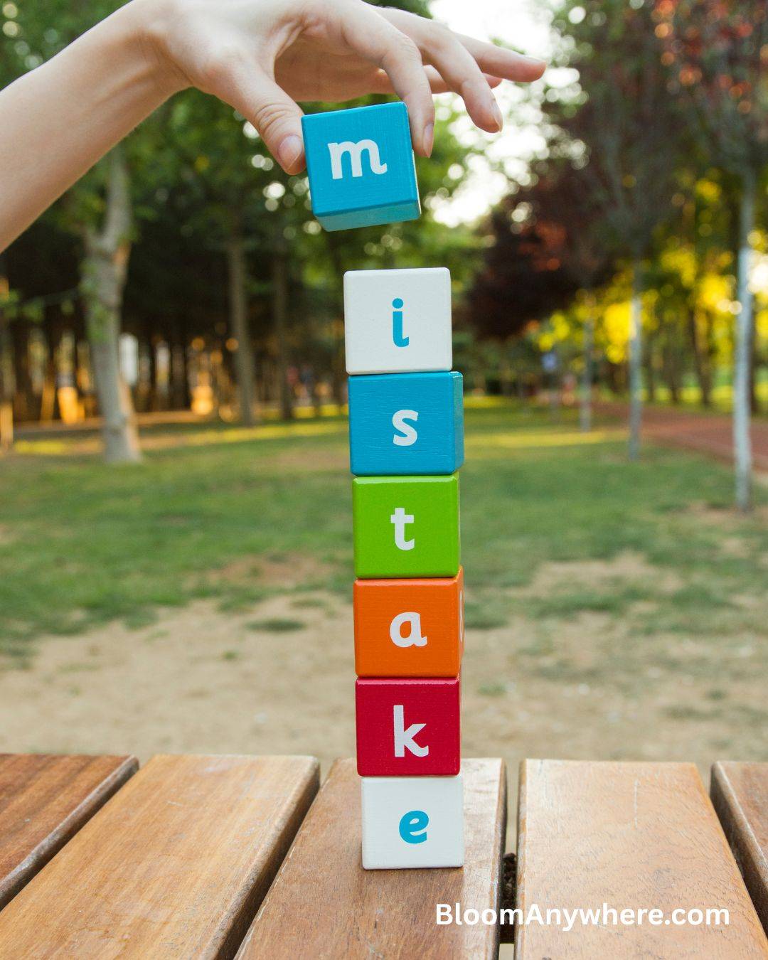 Colorful blocks stacked vertically on a table, spelling out the word mistake.