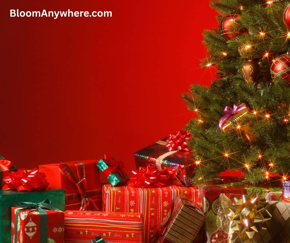 A Christmas tree with a stack of brightly wrapped presents next to it against a red background.