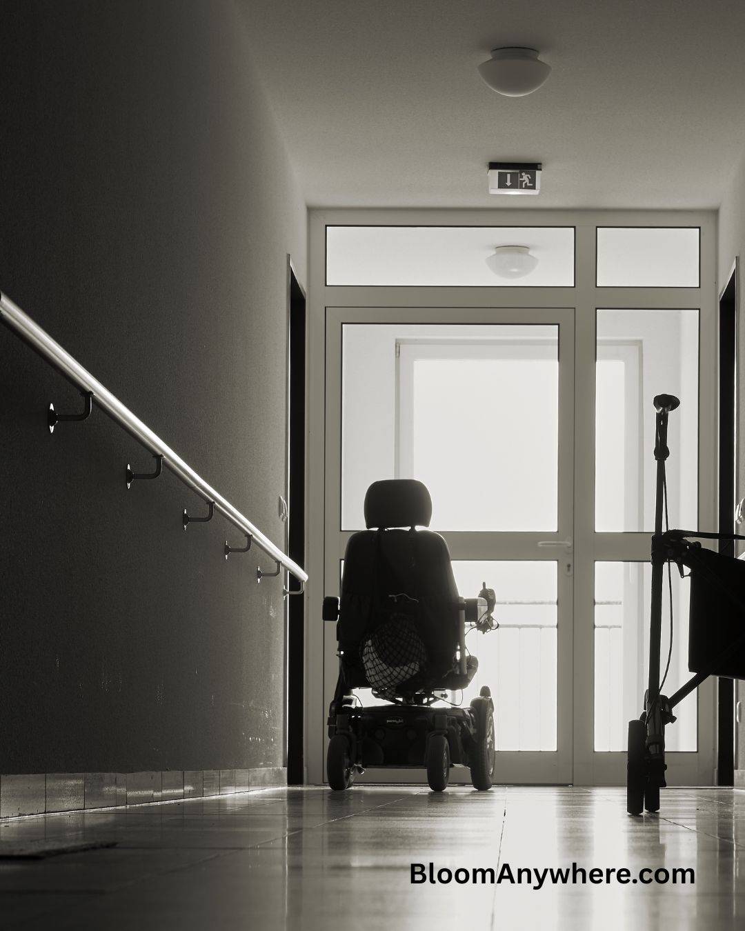 A black and white photograph of a wheelchair in a dark hallway