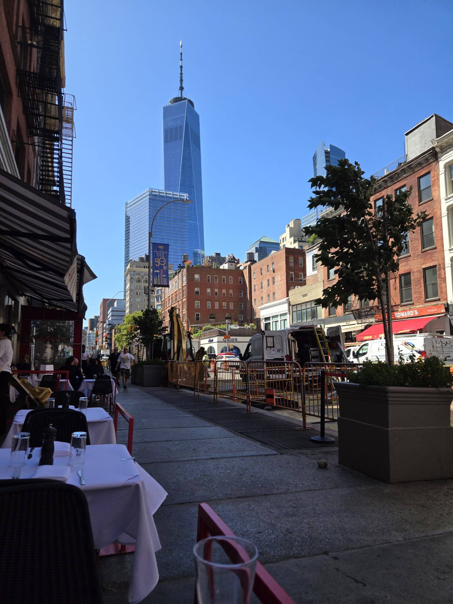 A view of a New York City street with the Freedom Tower in the distance