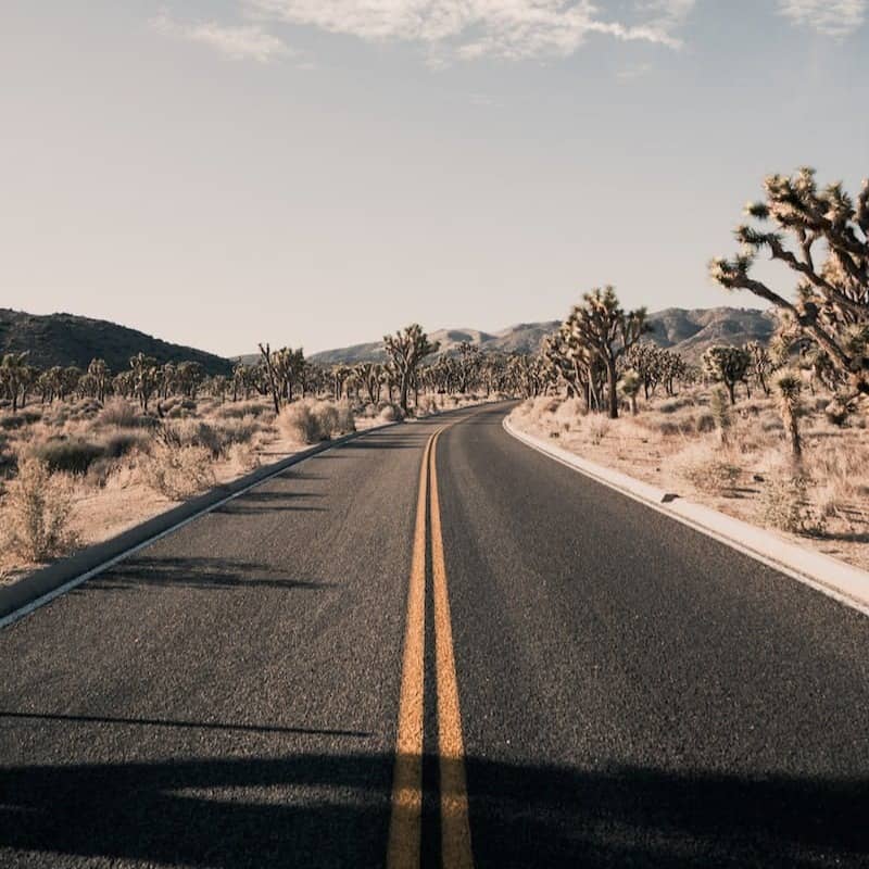 grey concrete road with no vehicle under white and blue skies