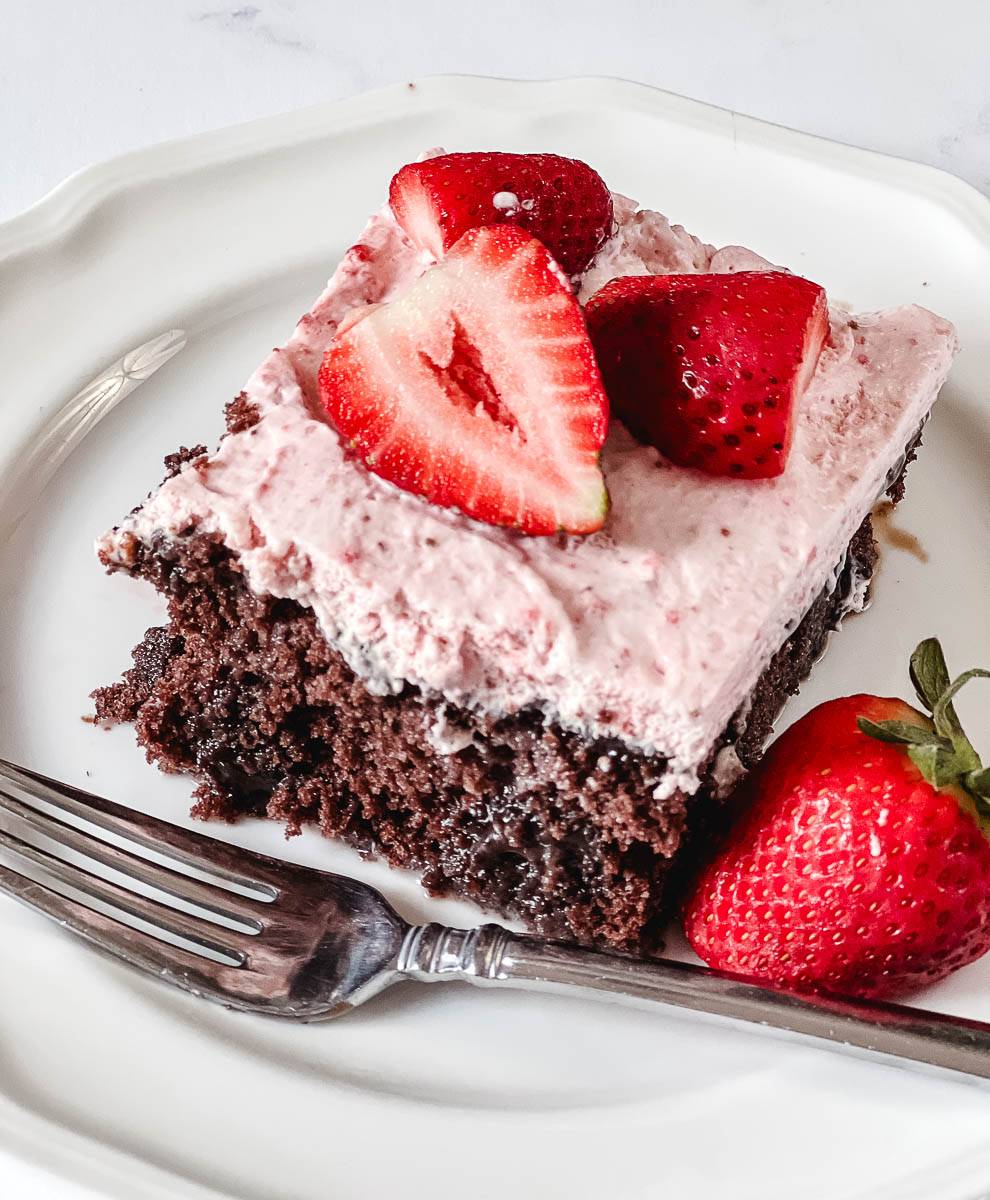 slice of cake on a white plate with strawberries and a fork.