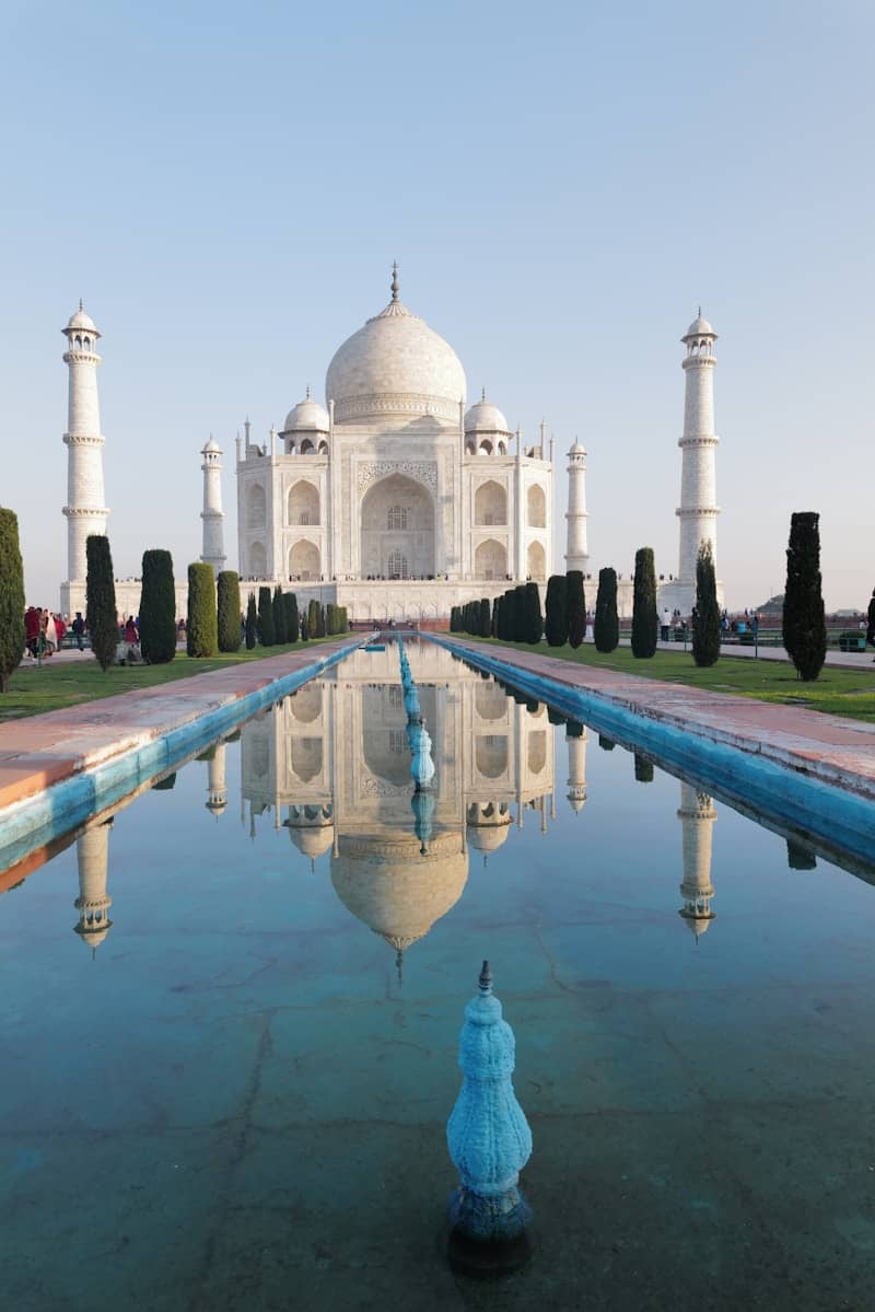 The taj mahal is reflected in the pool's water.