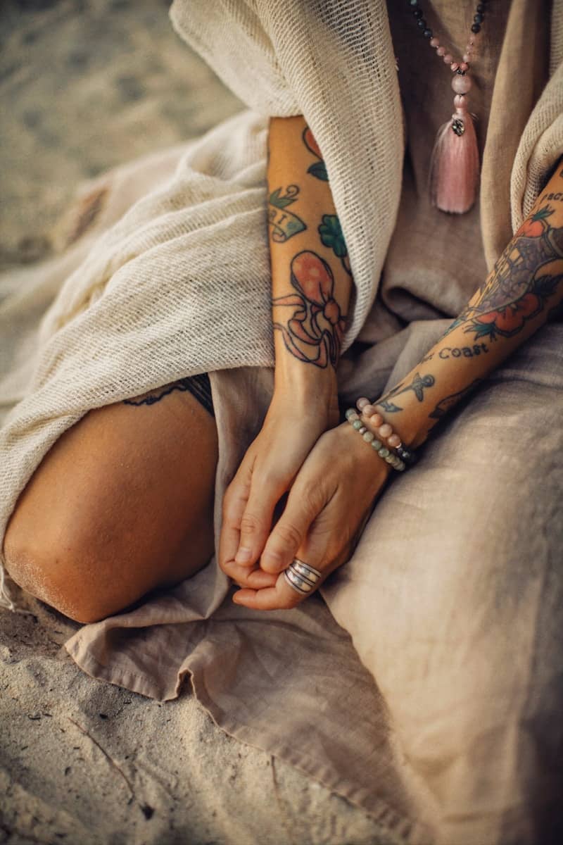 Tattooed arms and hands rest peacefully together.