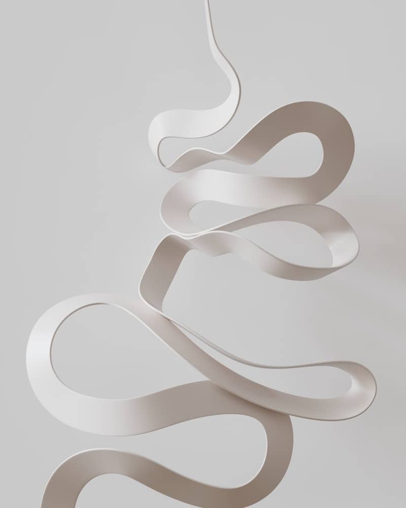 A white sculpture with a spiral design hanging from it's side